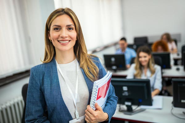 Young female teacher teaching young students a programming class in the classroom. - decorative